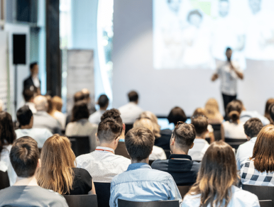 An audience of people watching a presentation at a conference