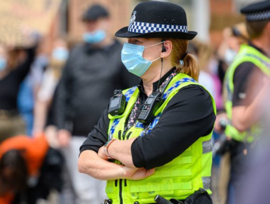 Police officer with arms crossed and wearing a face mask
