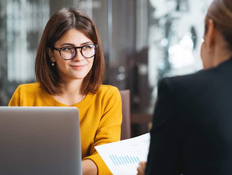 Two colleagues having a conversation over a laptop