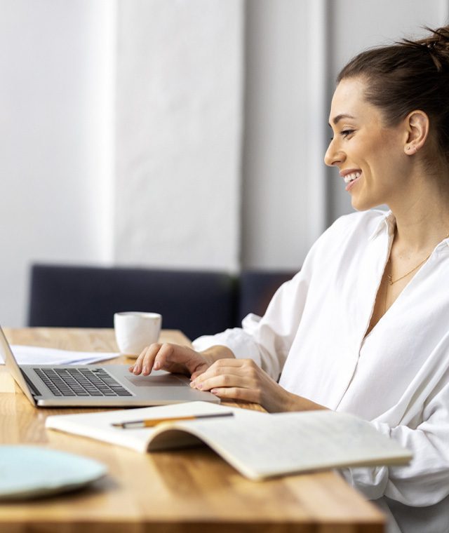 Person smiling while working on a laptop