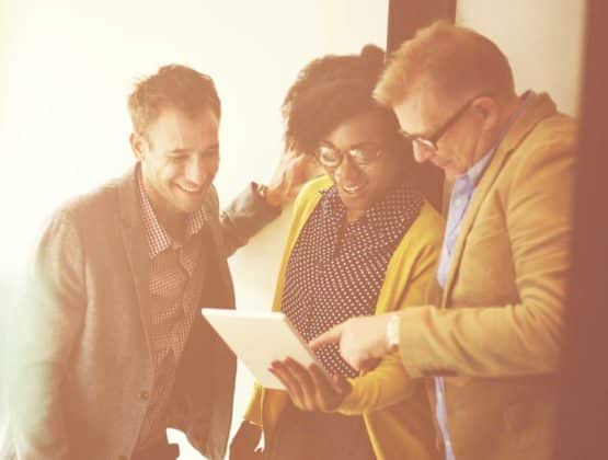 A group of colleagues in a conversation looking at an iPad
