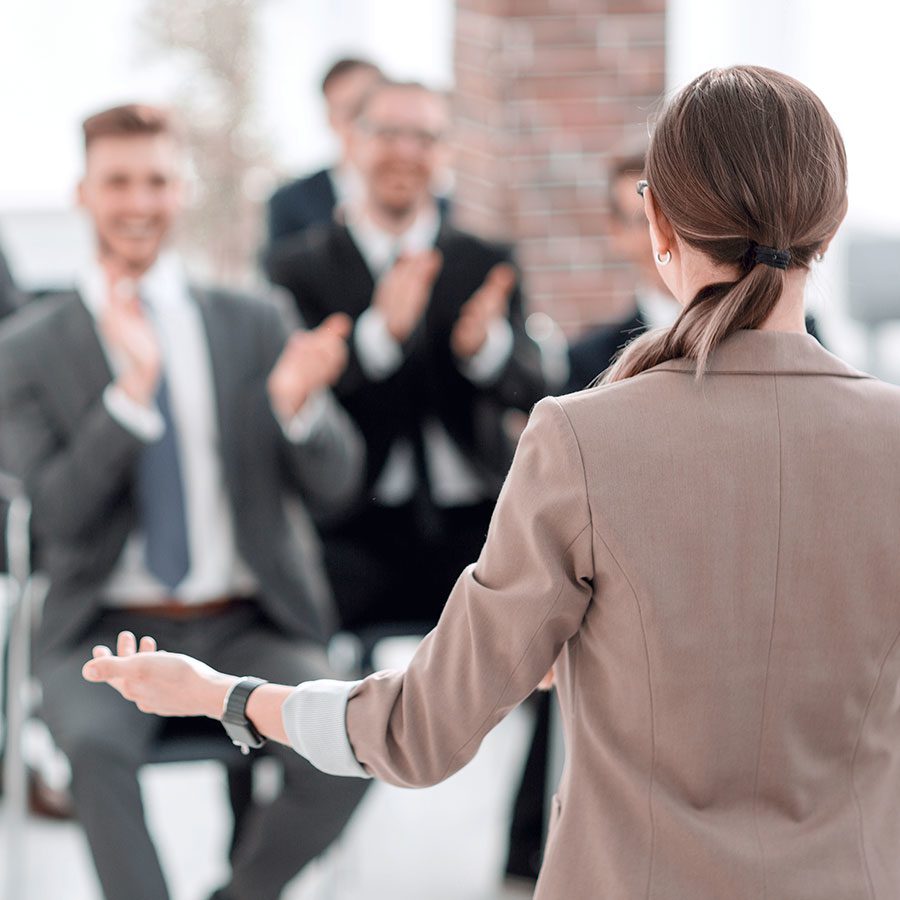 Woman at work event speaking in front of a group of professional people