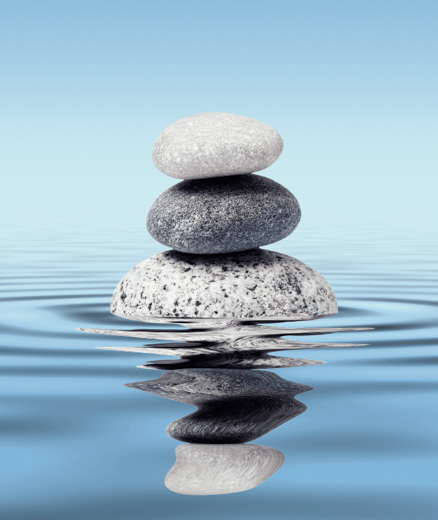 Three rocks balancing on top of each other in water.