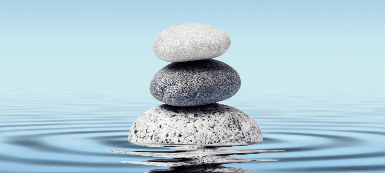 Three rocks balancing on top of each other in water.