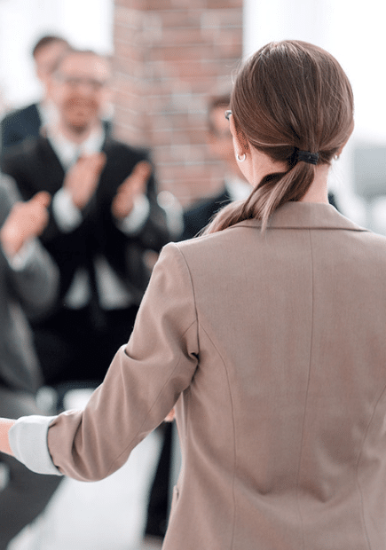 Woman wearing a blazer and presenting to a group of people