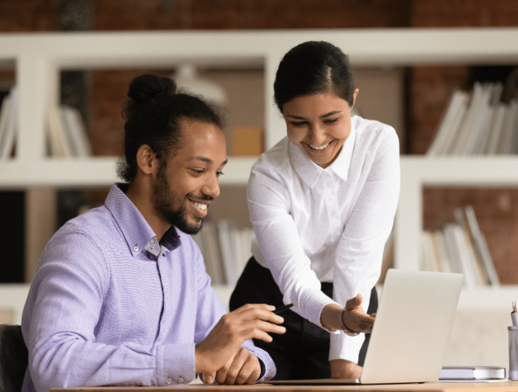 Two colleagues speaking and looking at a laptop together