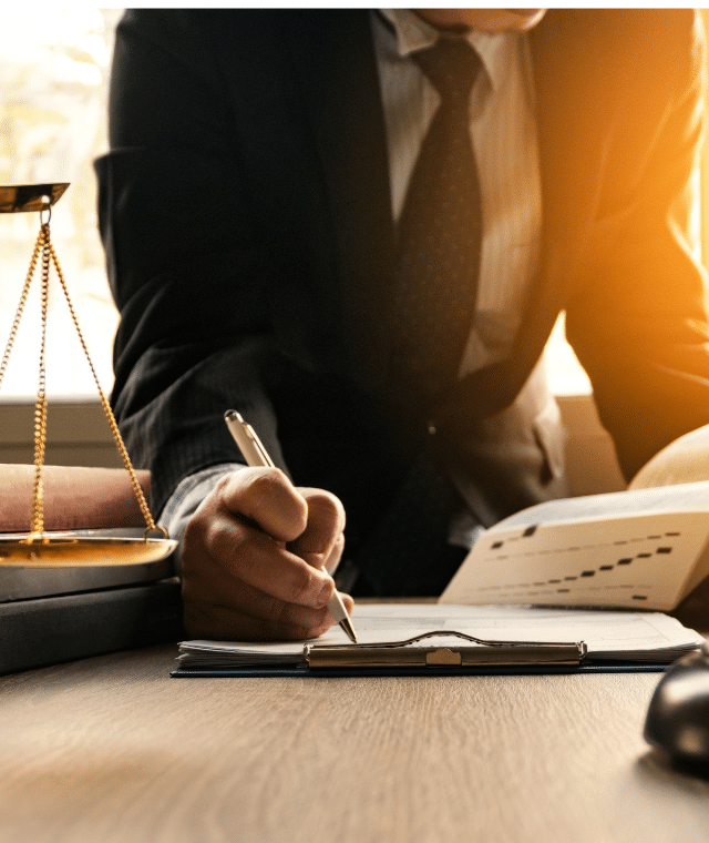 A person writing on a clipboard. There is law/court themed items on the desk where the person is writing.