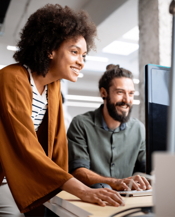 Two people looking at a computer in an office workplace.