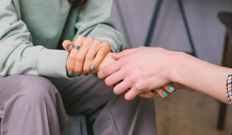 Two people holding hands in a supportive way