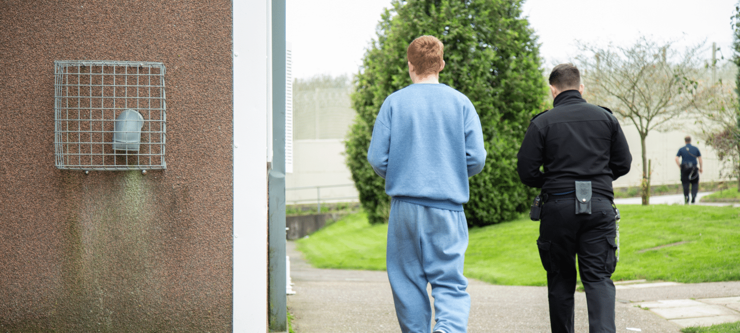 A prison officer and inmate walking together in a prison setting
