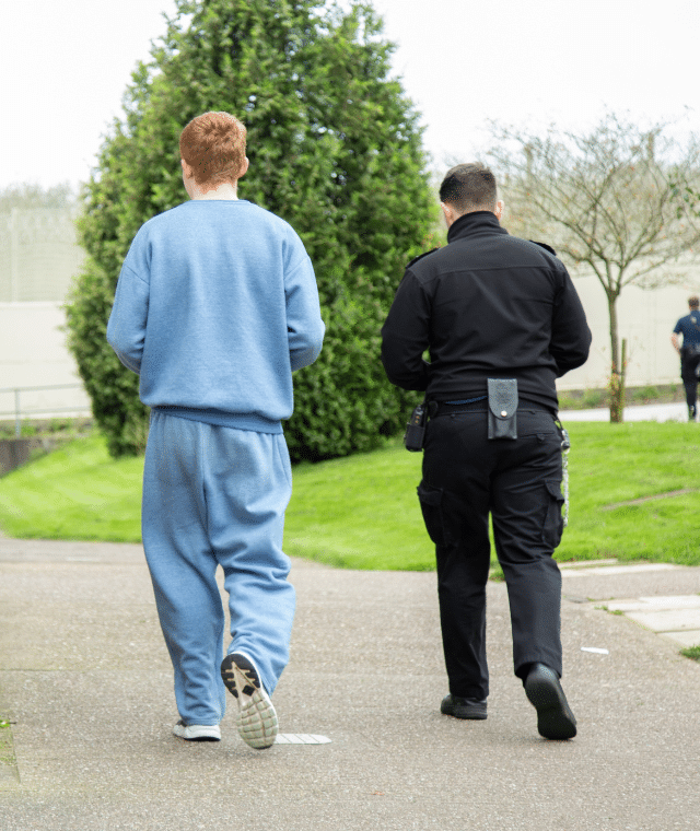 A prison officer and inmate walking together in a prison setting