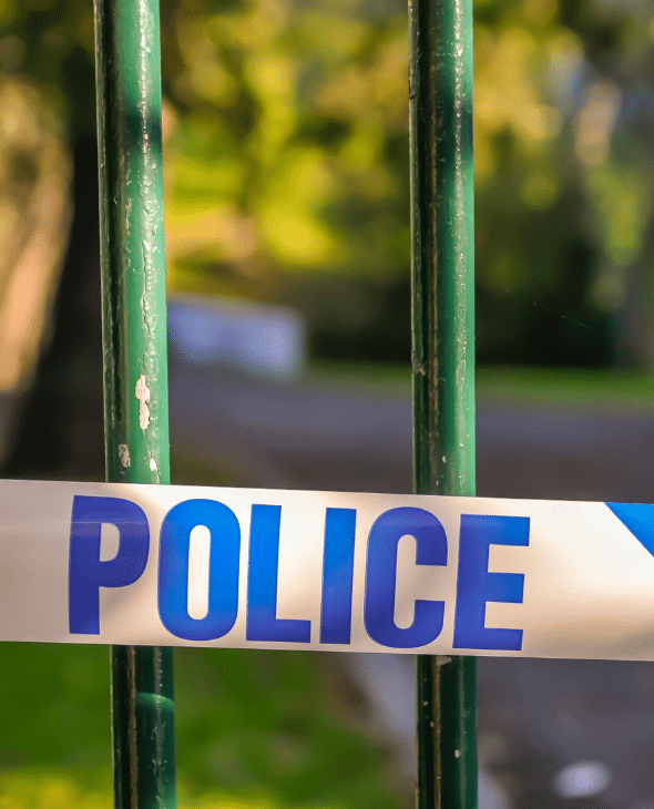 Police tape across a park fence