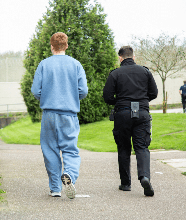 Offender and prison guard walking together in prison environment