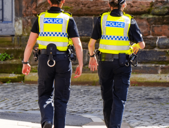 Two female police officers walking down a cobbled street