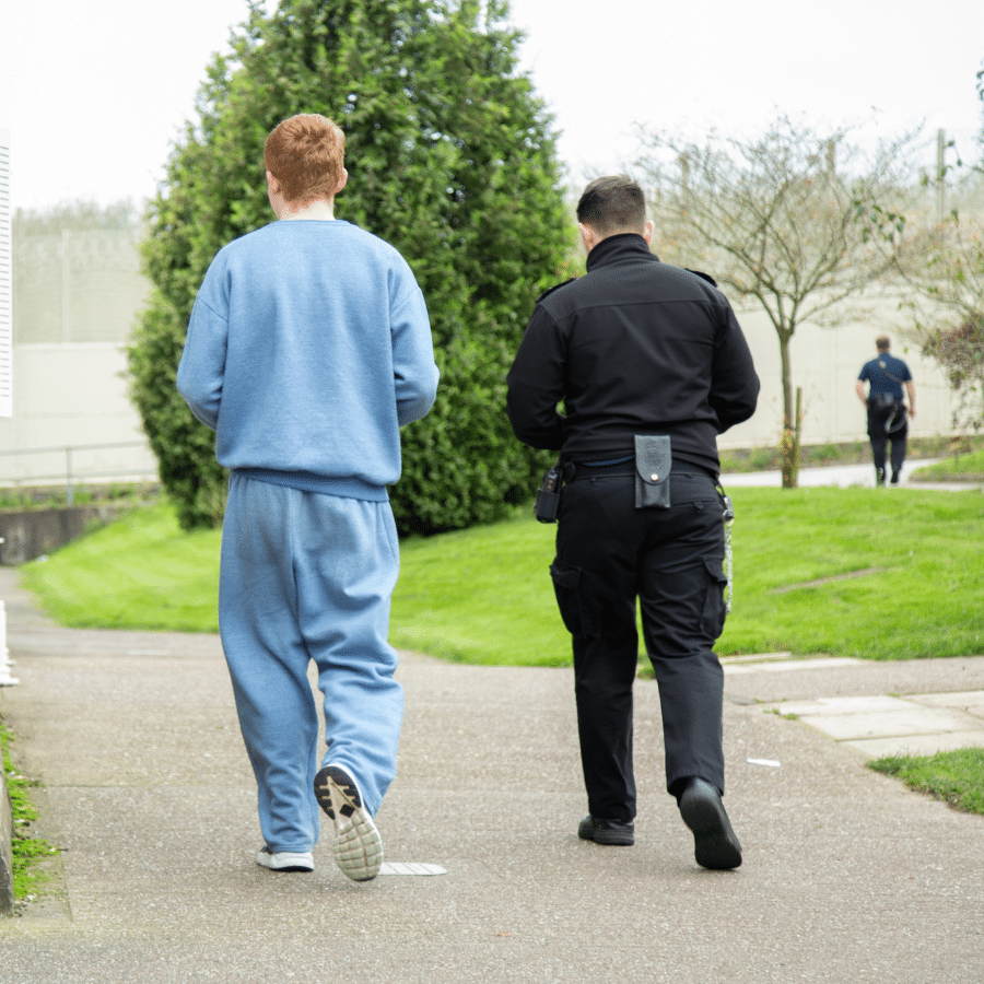 Offender and prison guard walking together in prison environment
