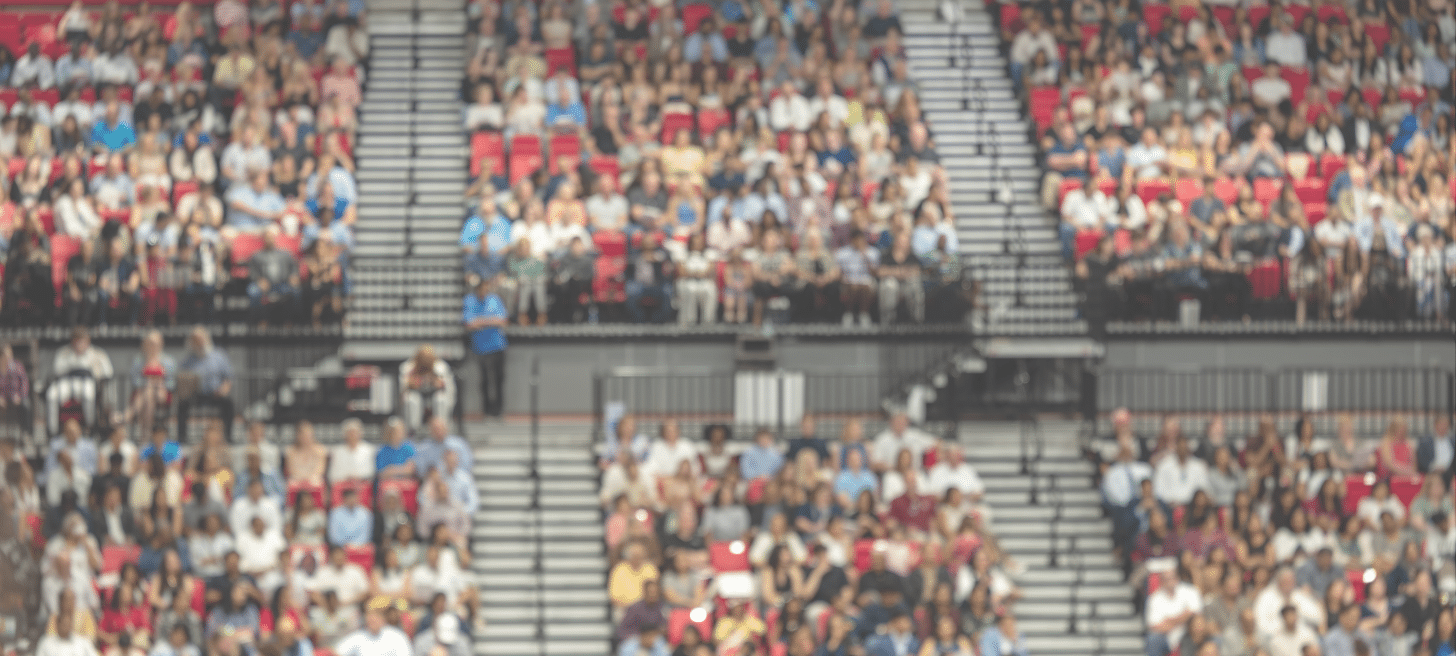 Blurred crowd of spectators sitting in stadium stands during large public event