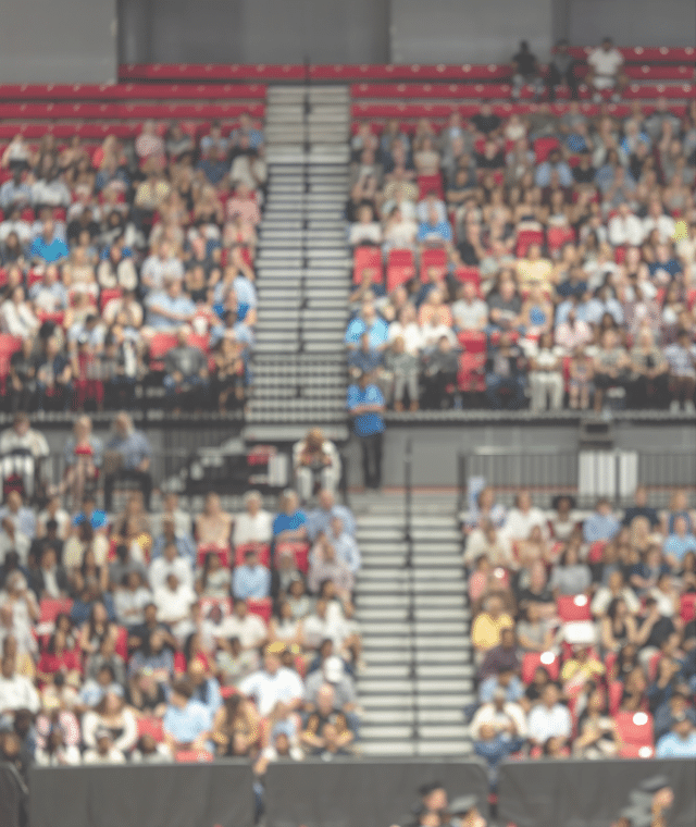 Blurred crowd of spectators sitting in stadium stands during large public event