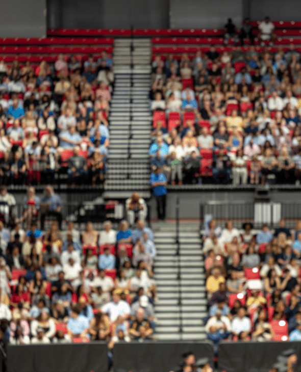 Blurred crowd of spectators sitting in stadium stands during large public event