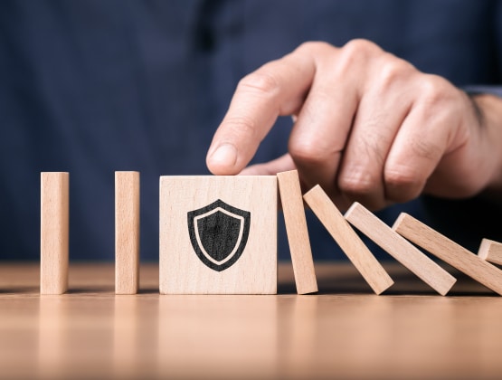 Wooden blocks arranged like domino with a shield symbol blocking the fall