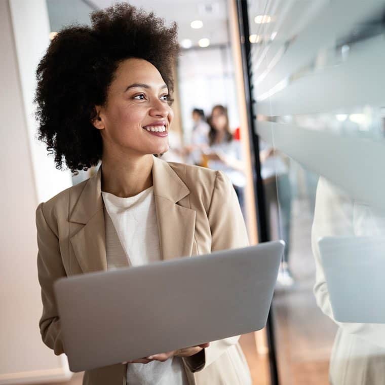 Woman walking through an office with a laptop