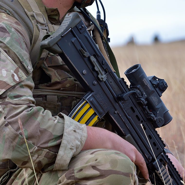 Person in the armed forces, crouched down with a gun