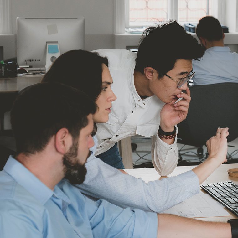 Group of office colleagues collaborating at a computer screen