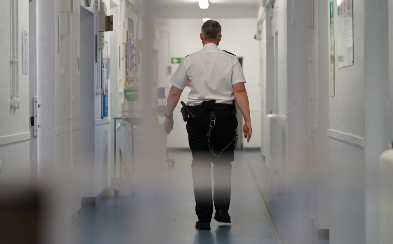 Prison officer walking down prison corridor.